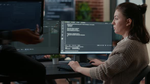 Junior Programer Sitting Down on Desk Showing Laptop with Source Code to Senior Dev