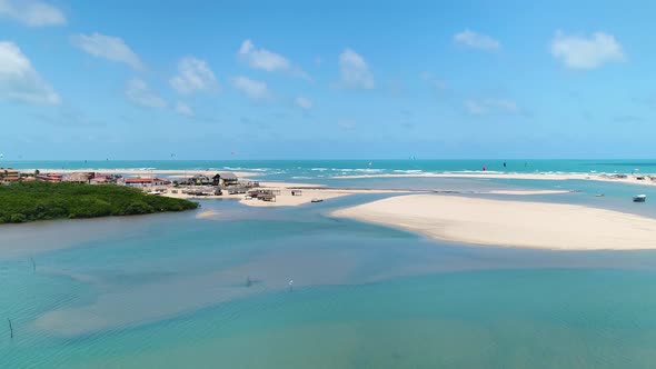 Aerial view of people practicing kitesurfing near a natural sand bank, Brazil.