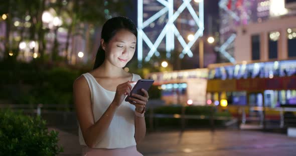 Woman work on mobile phone in city at night