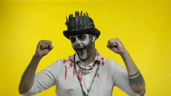 Scary Guy in Costume of Halloween Skeleton Wearing Earphones, Listening Music, Dancing, Celebrating
