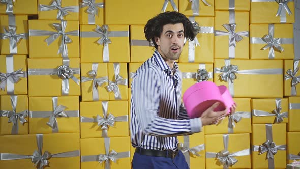 Happy Man Holding Gifts on a Yellow Background