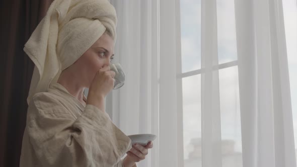 Pretty Woman Drinking Coffee by Window in Morning