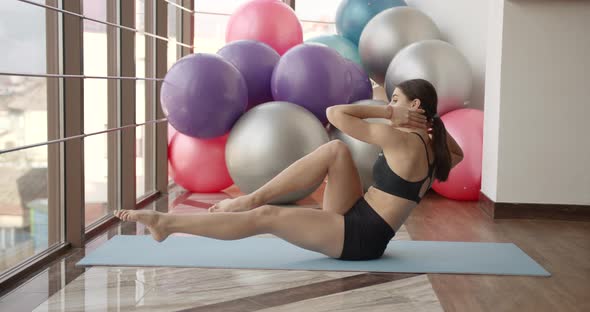 Athletic Woman Stretching on a Mat in a Fitness Studio