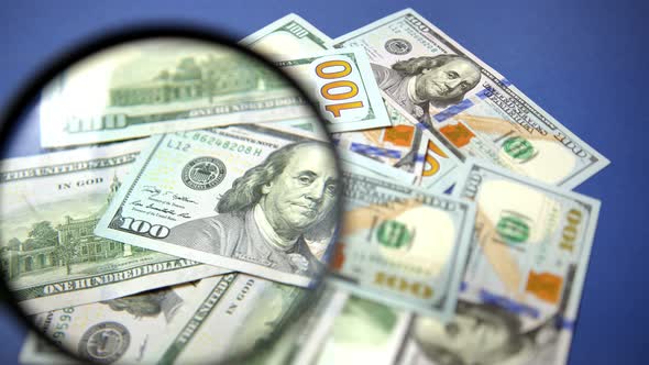 Checking 100 USD Banknotes With Magnifying Glass