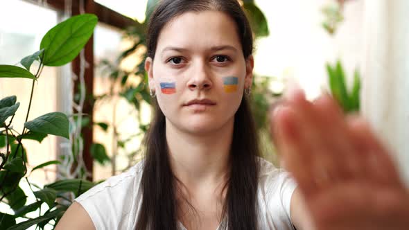Young RussianUkrainian Girl with the Flag of Ukraine and Russia on Her Face is Saying STOP