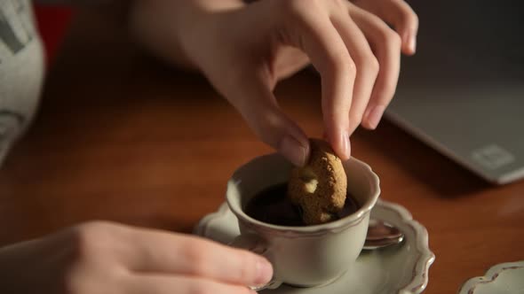 Hand dip cookie in cup of coffee