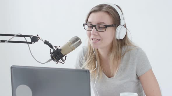 Concept of Streaming and Broadcasting. Young Cheerful Girl in the Studio Speaks Into a Microphone