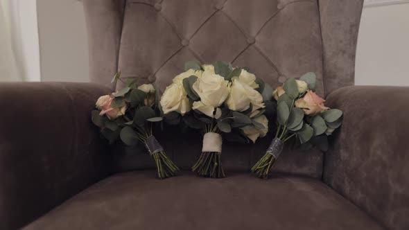 Three Wedding Bride and Bridesmaids Bouquets of White and Pink Roses Flowers Lie Down on Gray Chair