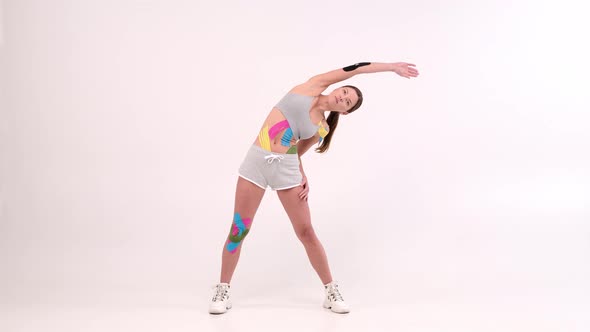full length portrait female athletes with a kinesiotape on her body doing fitness exercises 