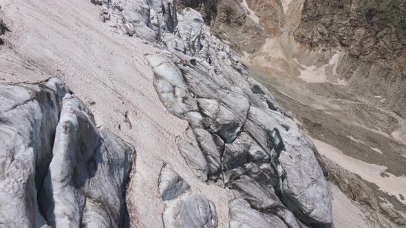 Glacier Covered with Stone Rocks Deep Cracks and Small Waterfalls