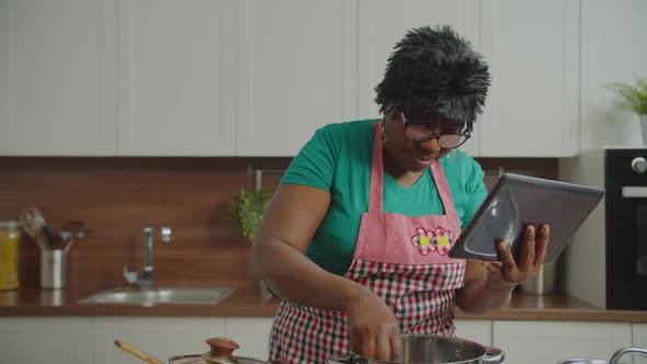 Elderly Female Preparing Meal Using Tablet Pc