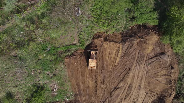 Top aerial view of bulldozer flattening surface on further construction site