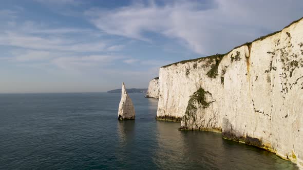 Aerial drone forward between stack and rocky cliff wall of Old Harry Rocks, Dorset