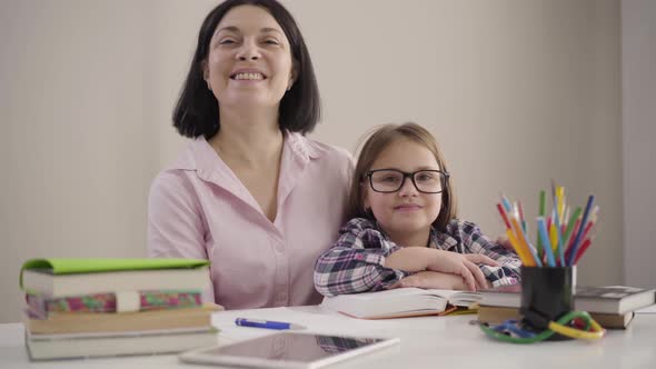 Portrait of Happy Caucasian Girl in Eyeglasses and Brunette Adult Woman Looking at Camera and