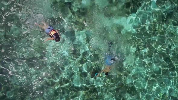 Aerial view of two people snorkeling with turtle in Panagsama Beach, Philippines.