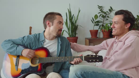 One of Lgbt Men is Showing Skills of Playing Guitar to His Boyfriend and Another One is Stroking a