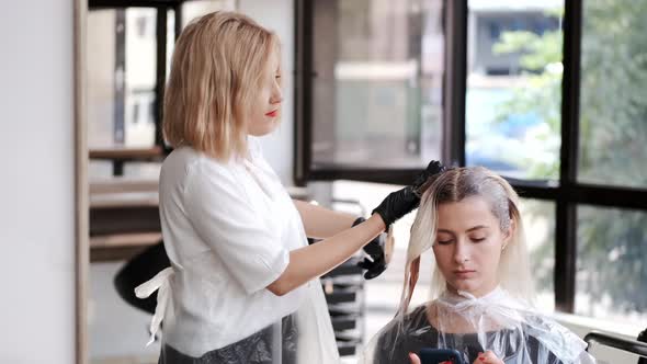 Hairdresser in Black Gloves Dyeing Client's Hair in Beauty Salon