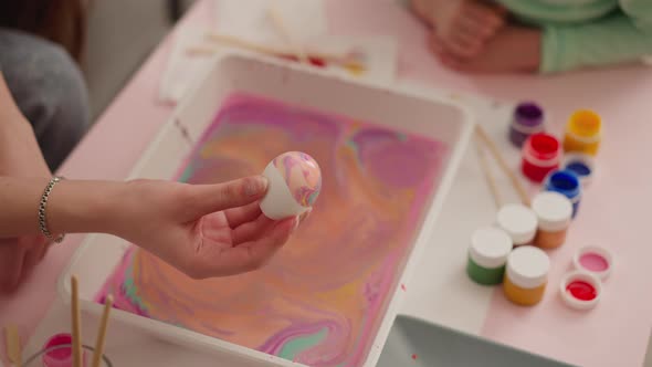 Teenage Girl Holds Easter Egg with Colored Marbling Patterns