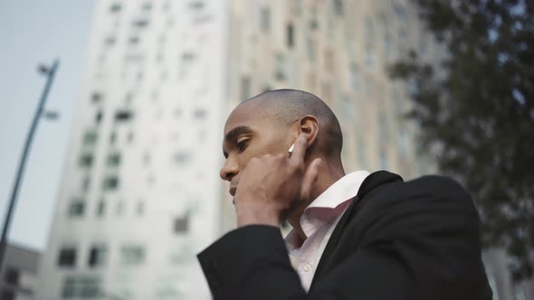 Smiling African businessman talking by phone in headphones