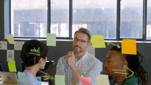 Business executives discussing over sticky note in office 4k