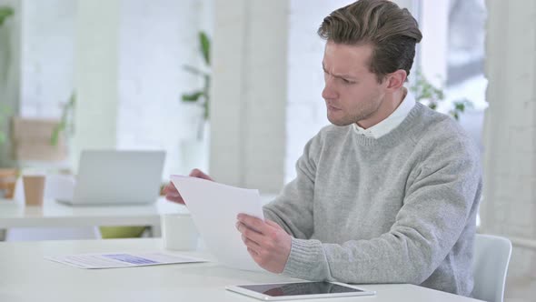 Creative Young Man Celebrating Success on Documents 