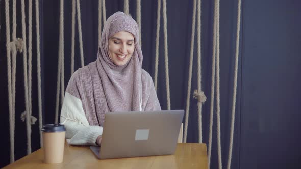 Joyful Moslem Lady Is Reading Messages in Notebook, Smiling and Writing Answer