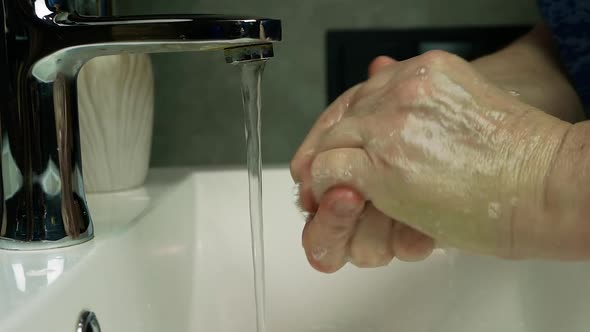 An Elderly Woman Washes Her Hands Under A Tap With Water, Washes Away The Dirt From Her Hands.