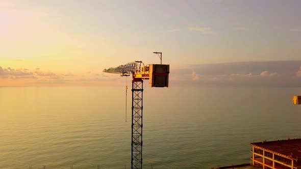 crane at sunset from a bird's-eye view, sun's rays pass through crane structure.