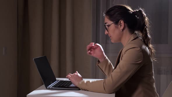 Pretty Brunette with Ponytail Types on Laptop at Home