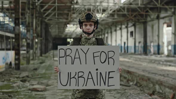 Military Woman Holding Banner with Phrase Pray for Ukraine