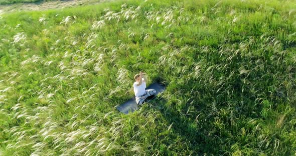 Girl meditates sitting on a beautiful green meadow