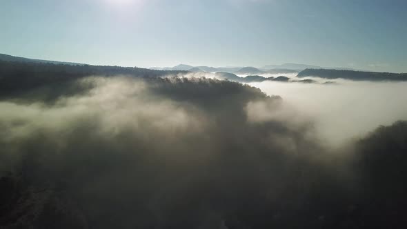 Aerial view of forests covered between clouds, beautiful blue sky with sunshine. Pantà de Sau, Taver