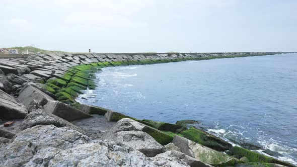 Panning shot of wave breaking rocks at seaside