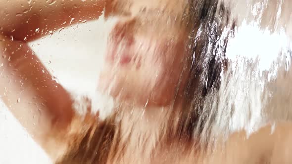 Portrait Through Wet Shower Glass on Smiling Happy Woman Washing Hair and Relaxing in Shower