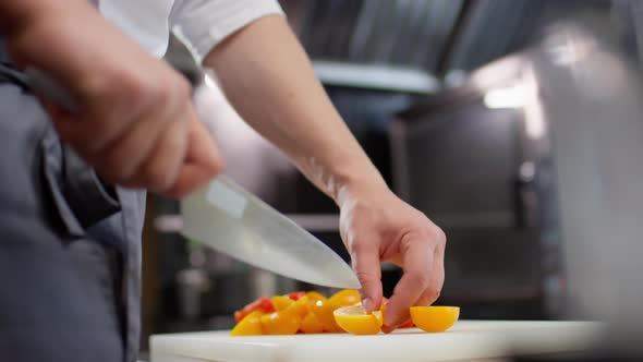 Hands of Chef Cutting Yellow Tomato