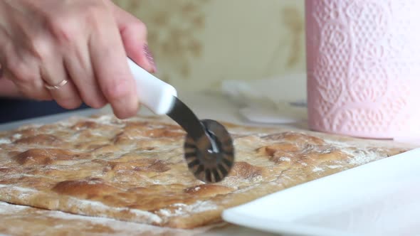 A Woman Cuts A Baked Cake Base. The Woman's Hands And Knife Are Visible. Close Up Shot.