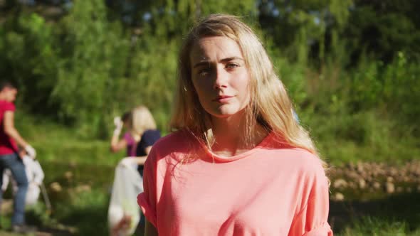 Caucasian woman smiling and looking at camera during river clean-up day