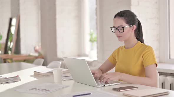 Focused Young Female Designer Working on Laptop in Modern Office