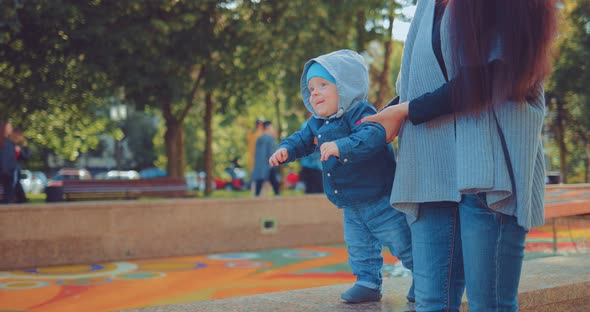 Baby First Steps Mom Supports Her Baby for a Walk in the Park