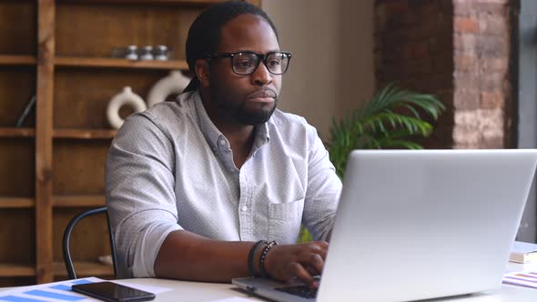 Sad Young African American Male Employee Using a Laptop