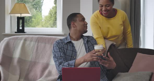 Portrait of Handsome African American Man Typing on Laptop Keyboard As Unrecognizable Woman Bringing