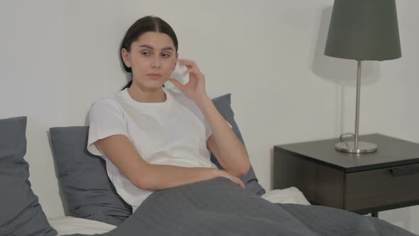 Pensive Hispanic Woman Thinking While Sitting in Bed