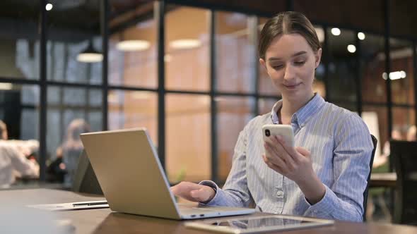 Young Woman Using Smartphone and Laptop