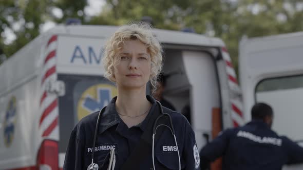 Female Paramedic Standing on Street with Ambulance Behind