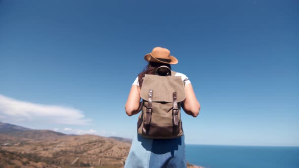 Carefree Young Backpacker Female Tourist Walking on Top of Mountain Enjoying Seascape Back View