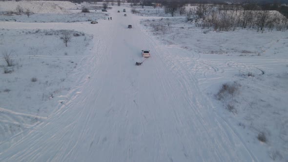 A man skiing with rope behind a car over snowy road, slow motion