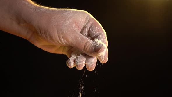 Male Hand Throws Flour on a Black Background
