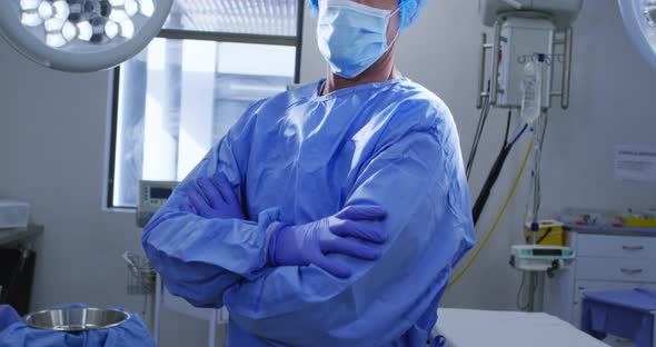 Portrait of male caucasian surgeon wearing face mask and scrubs in hospital