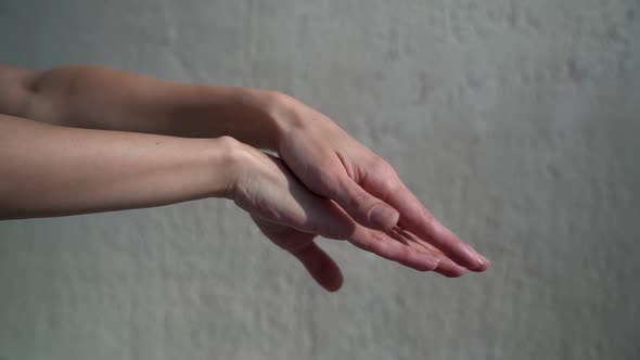 Woman with Natural Manicure Is Demonstrating Her Hands, Stroking Arms and Palms