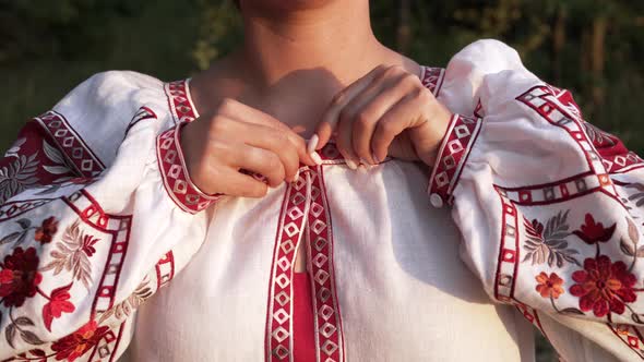 Ukrainian Woman Fastens Button on Embroidered Shirt with Traditional Ornament